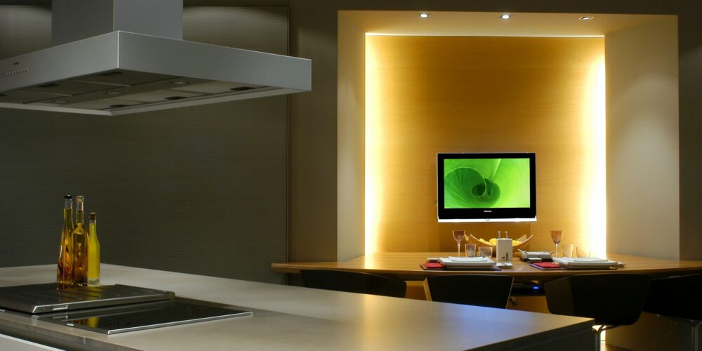 Cocinas en Casa Decor: Una cocina contemporánea que presenta un diseño minimalista con una isla de acero inoxidable, cocina integrada y un elegante comedor iluminado por luz ambiental.