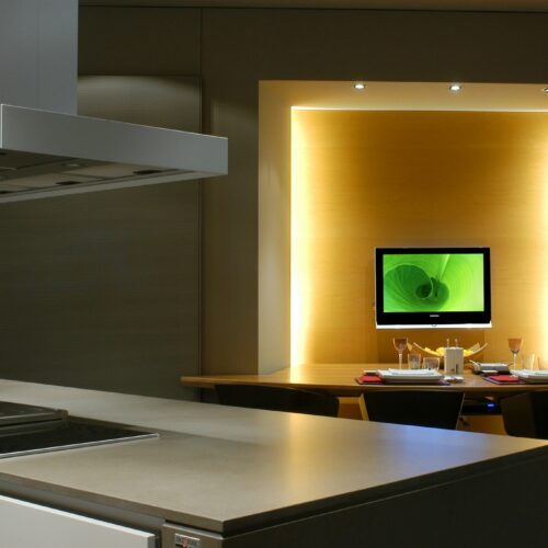 Cocinas en Casa Decor: Una cocina contemporánea que presenta un diseño minimalista con una isla de acero inoxidable, cocina integrada y un elegante comedor iluminado por luz ambiental.
