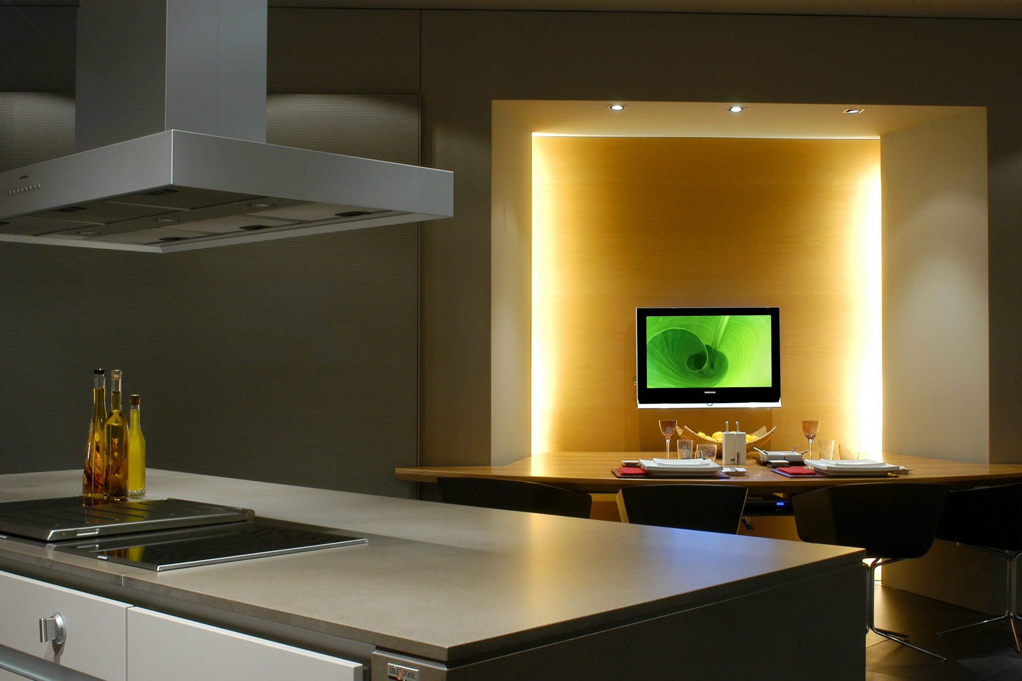 Cocinas en Casa Decor: Una cocina contemporánea que presenta un diseño minimalista con una isla de acero inoxidable, cocina integrada y un elegante comedor iluminado por luz ambiental.