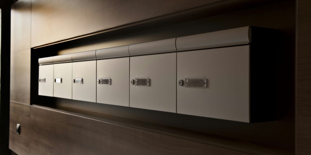 Diseño de interiores contemporáneo en Barcelona que muestra buzones elegantes integrados en una pared de madera oscura, enfatizando la estética minimalista y funcionalidad del espacio con iluminación suave.