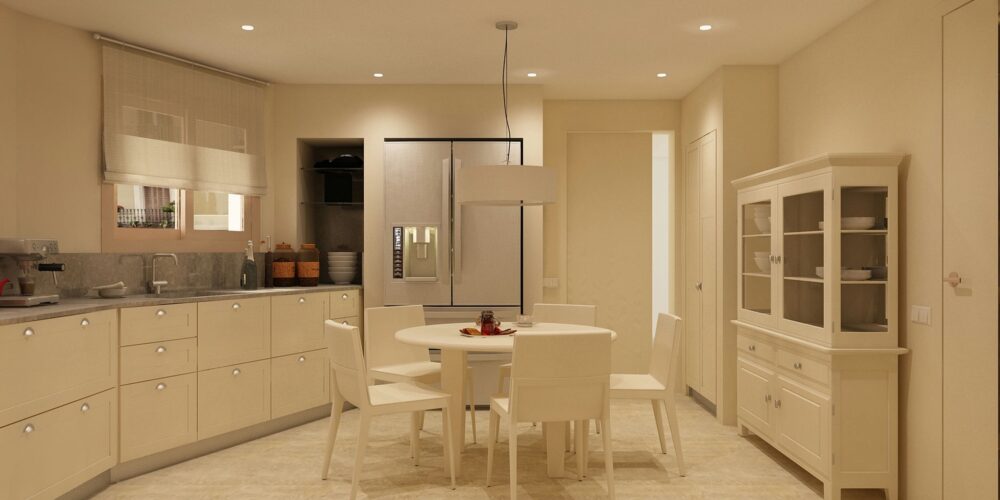 Cocina moderna en Barcelona con acabados de alta calidad, mueble de cocina en color crema, mesa redonda y sillas blancas, luz natural.