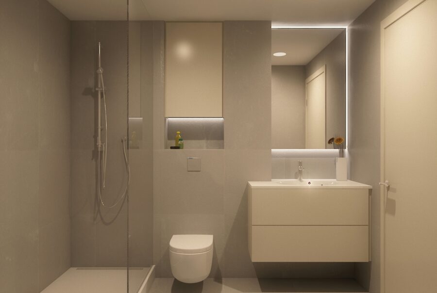 Diseño de interiores de un baño de alta gama en Barcelona, con una distribución elegante en tonos grises, ducha espaciosa con partición de vidrio, inodoro minimalista y vanidad estilosa con iluminación integrada.