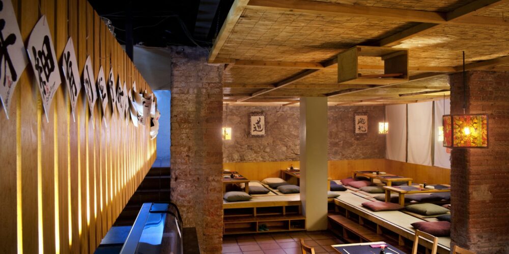 Interior de un restaurante en Barcelona con diseño moderno, materiales de calidad como madera y piedra, y elementos decorativos japoneses.