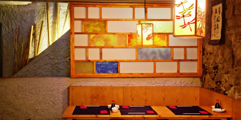 Comedor moderno en Barcelona con asientos de madera, iluminación sofisticada y diseño de paredes coloridas.