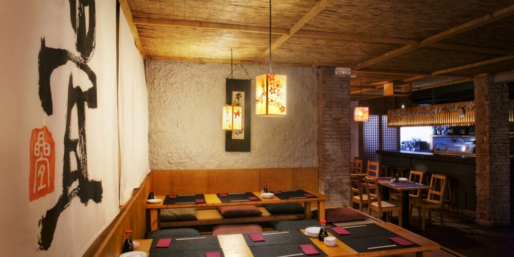Interior de un restaurante moderno en Barcelona, combinando estética contemporánea y funcionalidad con materiales de alta calidad como madera y piedra, techos de bambú y luminarias artísticas.