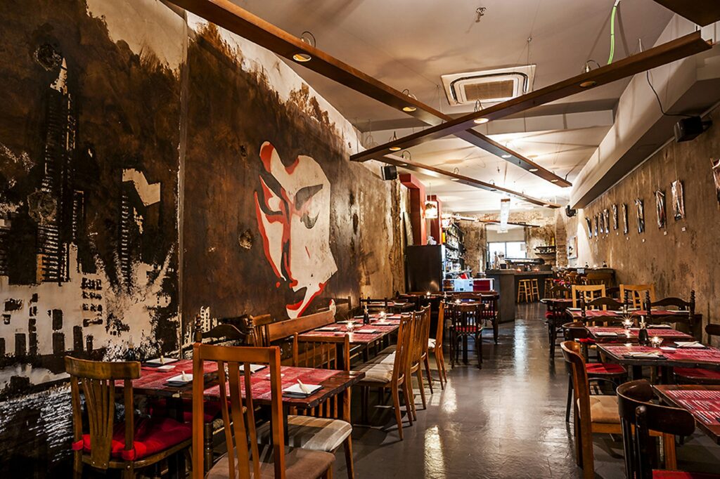 Interior moderno de restaurante en Barcelona con mural artístico Vista interior de un restaurante contemporáneo en Barcelona, destacando un mural artístico en la pared y muebles de madera con detalles arquitectónicos elegantes.