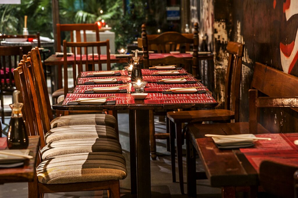 Restaurante Moderno en Barcelona con Diseño Interior Elegante Vista interior de un restaurante contemporáneo en Barcelona, con mesas y sillas de madera, manteles rojos y velas, resaltando un diseño funcional y estético.