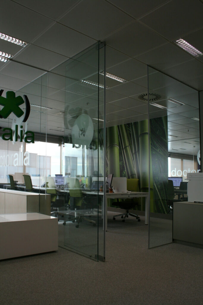 Espacio de Oficina Moderna con Sala de Reuniones con Paredes de Vidrio y Acentos Verdes Una oficina contemporánea que presenta una sala de reuniones con paredes de vidrio, acentos verdes, escritorios organizados con computadoras y sillas ergonómicas. La oficina cuenta con un mural de tema de bambú y un gran logotipo de la empresa en la pared de vidrio, creando una atmósfera profesional y acogedora.