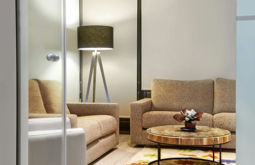 Sala de Estar Contemporánea Acogedora con Sofás Elegantes Un espacio de vida cálido y acogedor que presenta dos sofás en tonos neutros, una mesa de café redonda de madera con una pequeña planta decorativa y una lámpara de pie moderna en un ambiente iluminado suavemente.