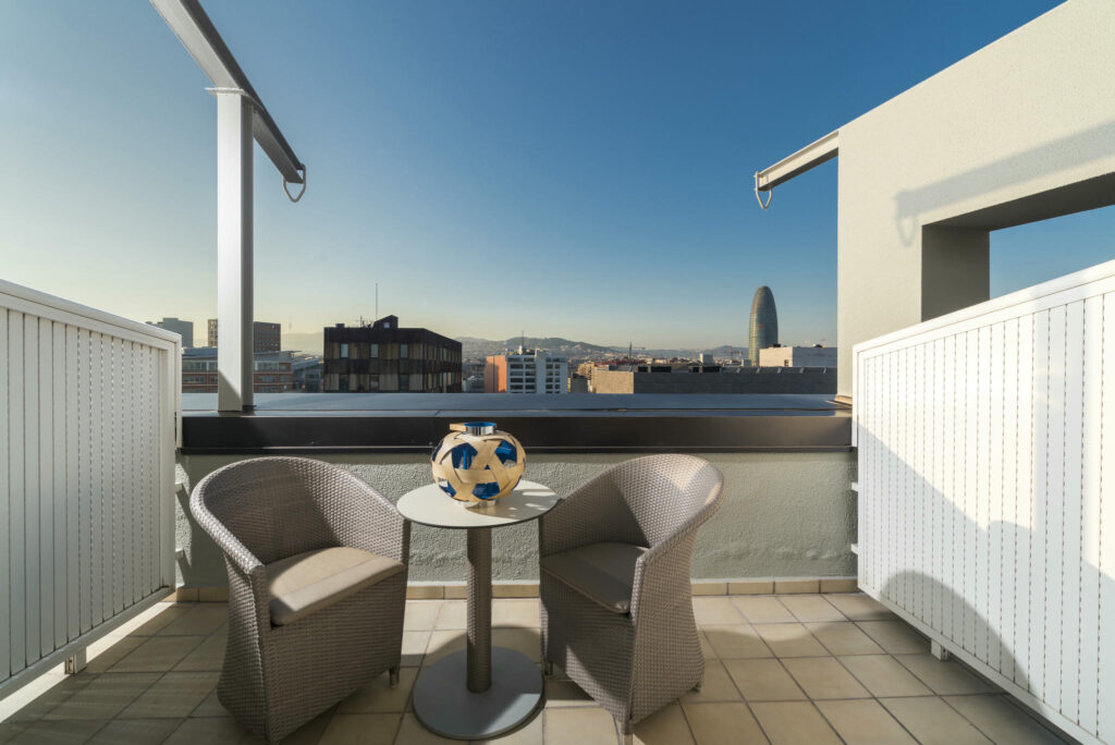 Terraza Moderna con Estilo Terraza elegante con sillas de mimbre y vistas urbanas impresionantes.