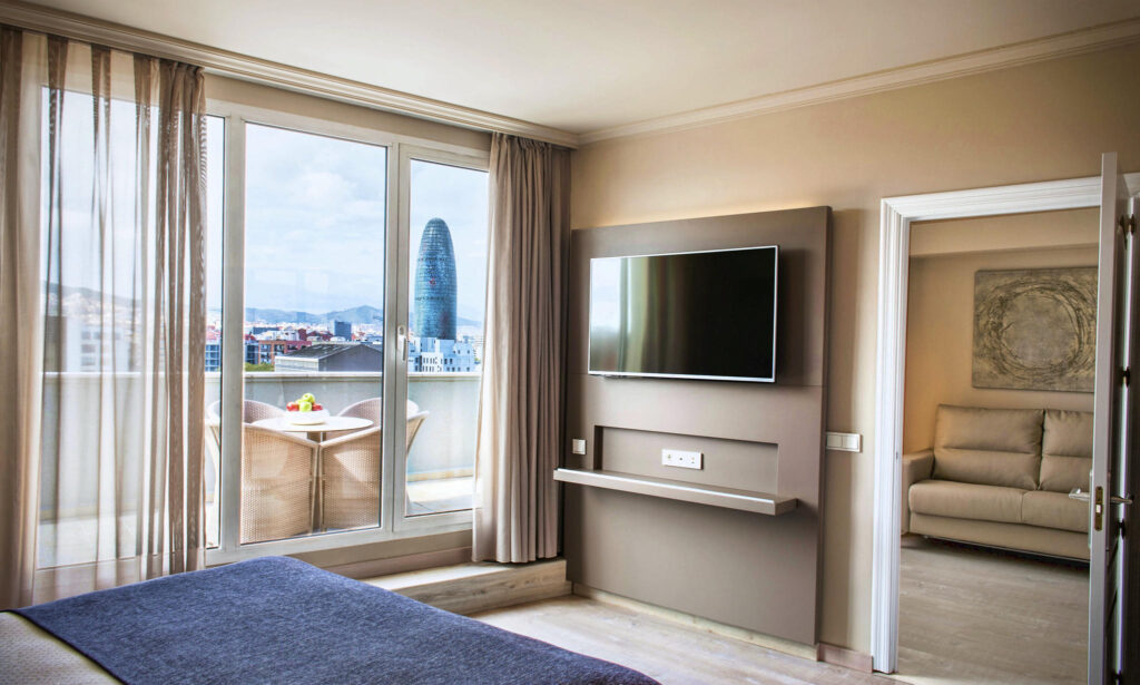 Hotel Pere IV: Dormitorio minimalista con televisor y ventanas grandes.