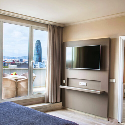 Hotel Pere IV: Dormitorio minimalista con televisor y ventanas grandes.