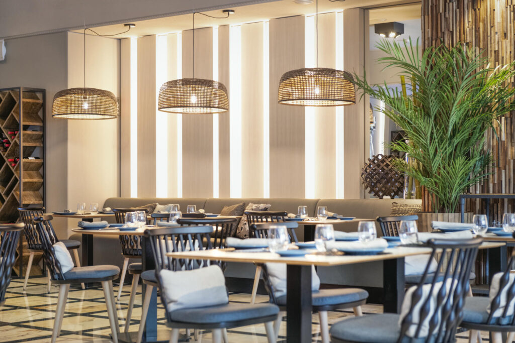 Restaurante moderno y acogedor Interior de restaurante con mesas de madera y lámparas de mimbre