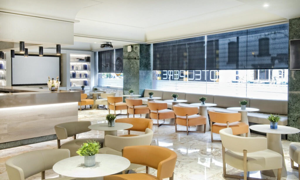 Diseño Interior Elegante y Moderno Sala contemporánea con asientos naranjas y mesas en un entorno acogedor y elegante.