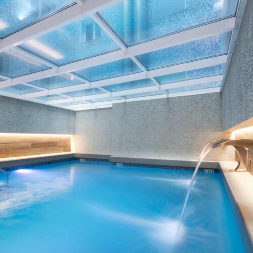 Piscina elegante con luz natural y acabados en mármol.