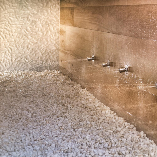 Baño moderno con detalles en piedra y acero inoxidable.