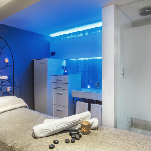 Spa interior moderno con luz azul y elementos de piedra.