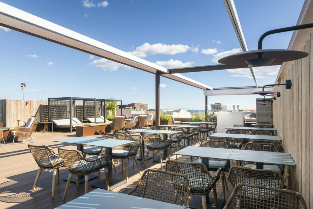 Terraza moderna con muebles de mimbre Terraza elegante con muebles de mimbre y mesas de metal