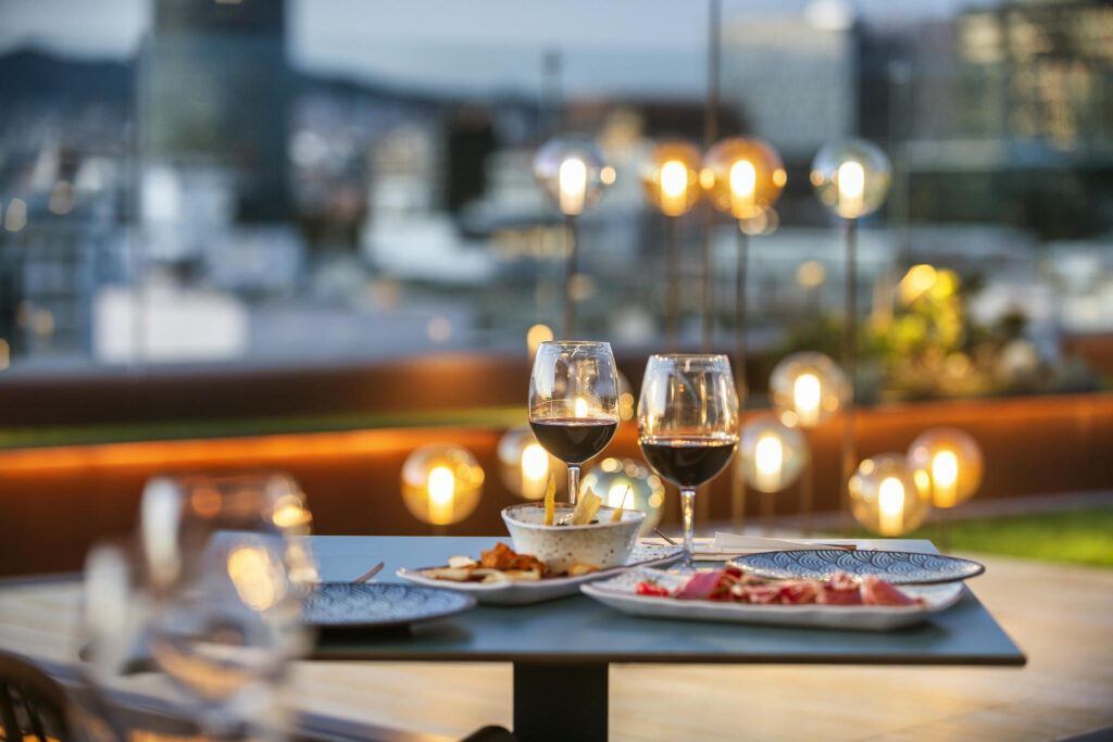 Cena elegante en terraza moderna Mesa en terraza con copas de vino y platos gourmet decorados