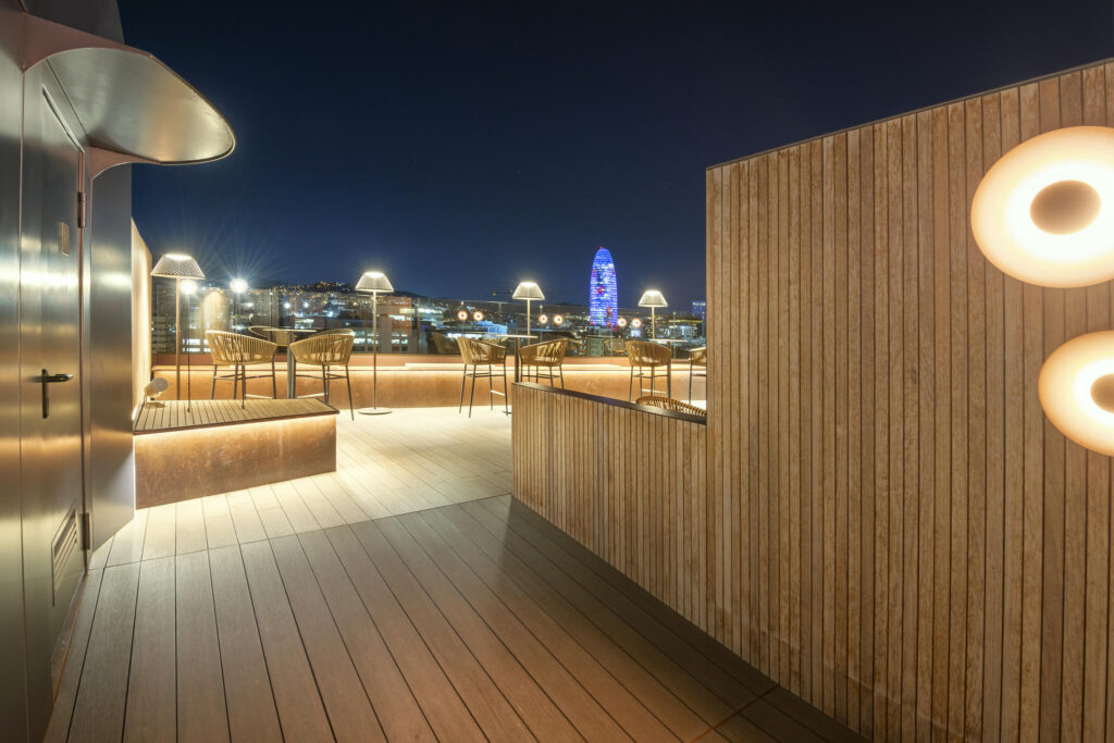 Terraza Moderna y Acogedora Terraza contemporánea con bancos de madera y vistas nocturnas de la ciudad.