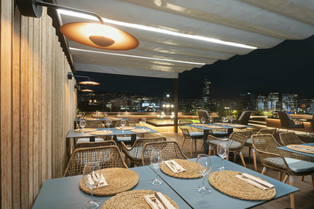 Terraza moderna iluminada Terraza de un restaurante con sillas de mimbre y mesas en tonos azules.
