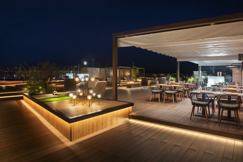 Terraza moderna con iluminación cálida Terraza iluminada con mobiliario de madera y diseño contemporáneo.