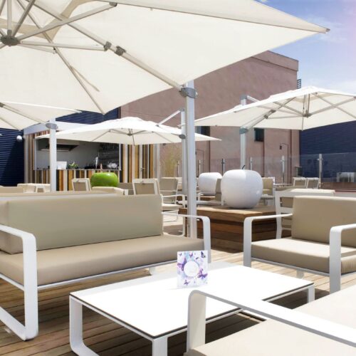 Terraza elegante con sofás beige y sombrillas de diseño contemporáneo