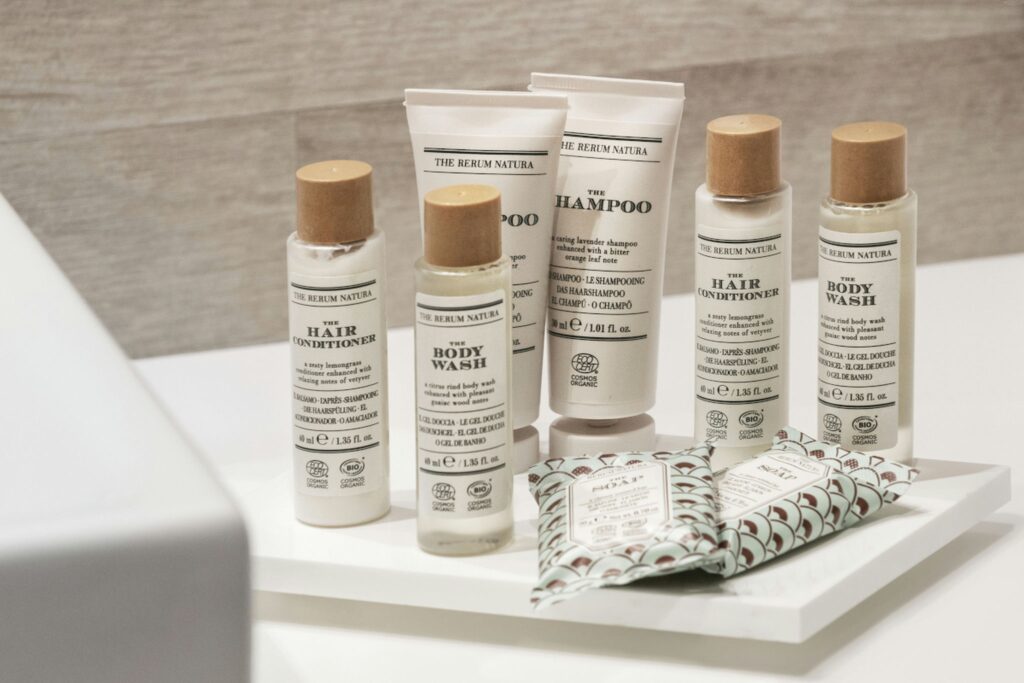 Baño minimalista con productos elegantes Botellas modernas de champú y gel sobre bandeja blanca en baño de diseño contemporáneo.