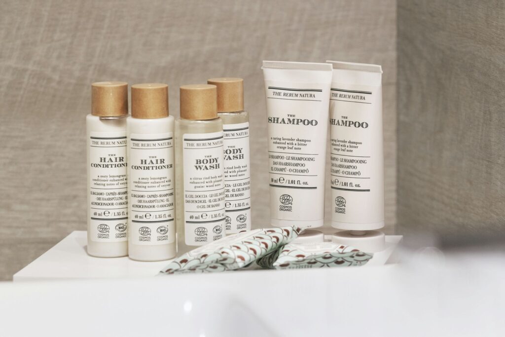 Lujosos productos de baño en diseño minimalista Frascos de productos de baño orgánicos con diseño minimalista, incluyendo acondicionador, champú y gel de ducha en etiquetas blanco y negro sobre fondo de madera suave.