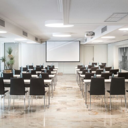 Salón de conferencias moderno con mesas y proyector.