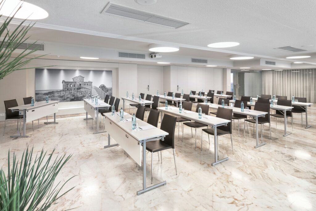 Sala de Conferencias Elegante Sala moderna con mesas blancas y sillas de diseño oscuro.