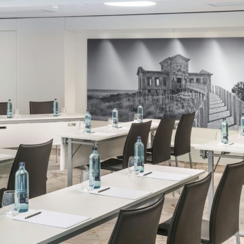 Sala de reuniones moderna con mesas blancas y sillas de cuero marrón