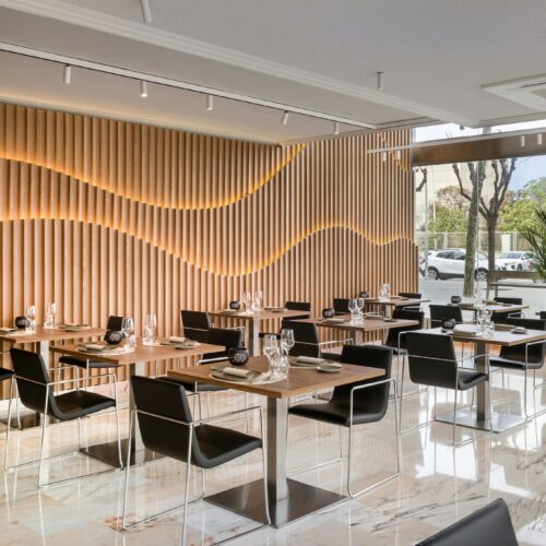 Comedor contemporáneo con mesas de cristal y diseño en madera.