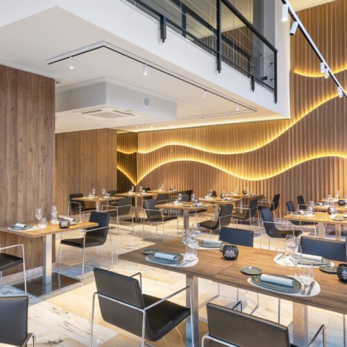 Restaurante moderno con madera y iluminación cálida destacada.