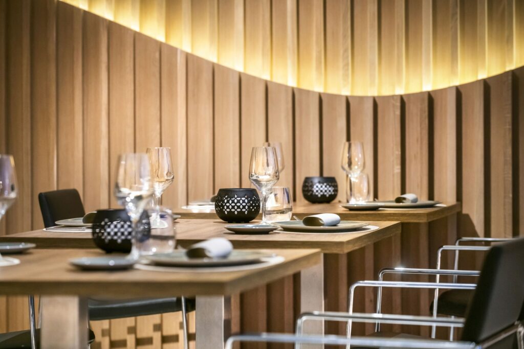 Comedor Moderno: Estilo Minimalista con Toques Elegantes Comedor elegante con mesas de madera, sillas de acrílico transparente y vajilla minimalista en tonos negros y dorados.