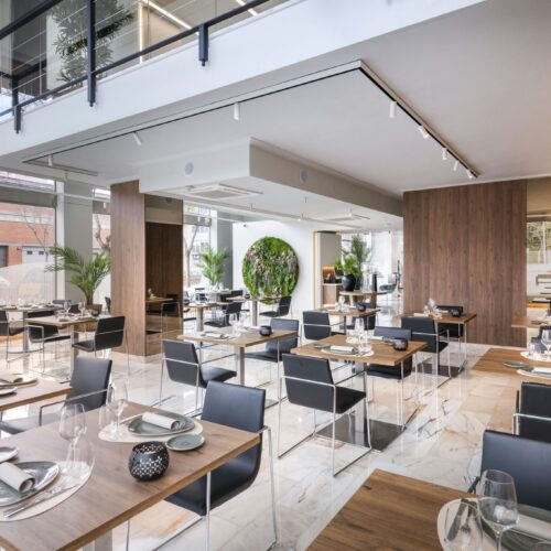 Interior de un restaurante contemporáneo con mesas de madera y sillas negras.