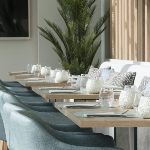 Comedor elegante con sillas azules y mesas de madera clara.