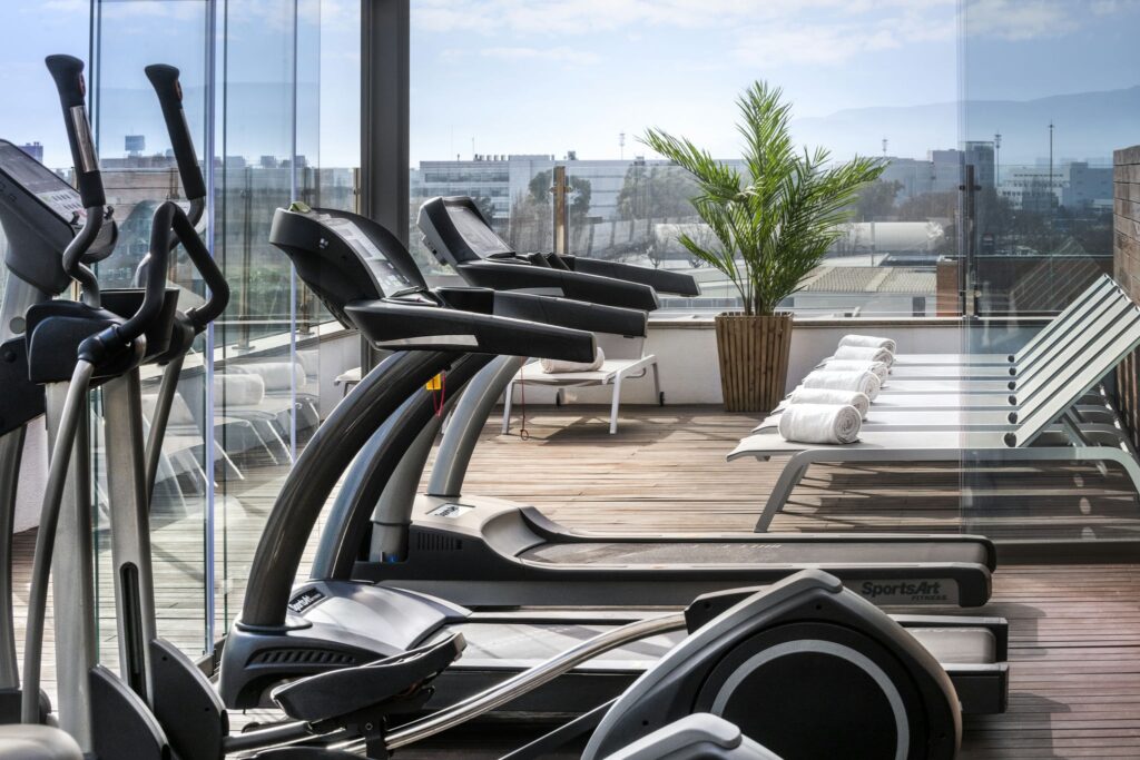 Gimnasio moderno con vistas Gimnasio con elípticas y área de relax exterior