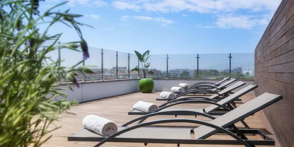 Terraza contemporánea con tumbonas de metal y plantas decorativas.