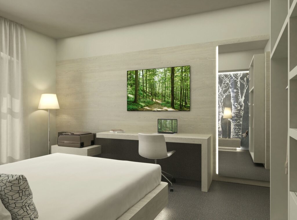Diseño de interiores contemporáneo en un dormitorio moderno en Barcelona Moderno dormitorio en Barcelona con diseño de interiores contemporáneo, que incluye una cama minimalista, escritorio funcional, silla blanca y lámpara de pie. Destacan un cuadro de paisaje natural, iluminación natural y materiales de alta calidad como madera y acabados en tono neutro.