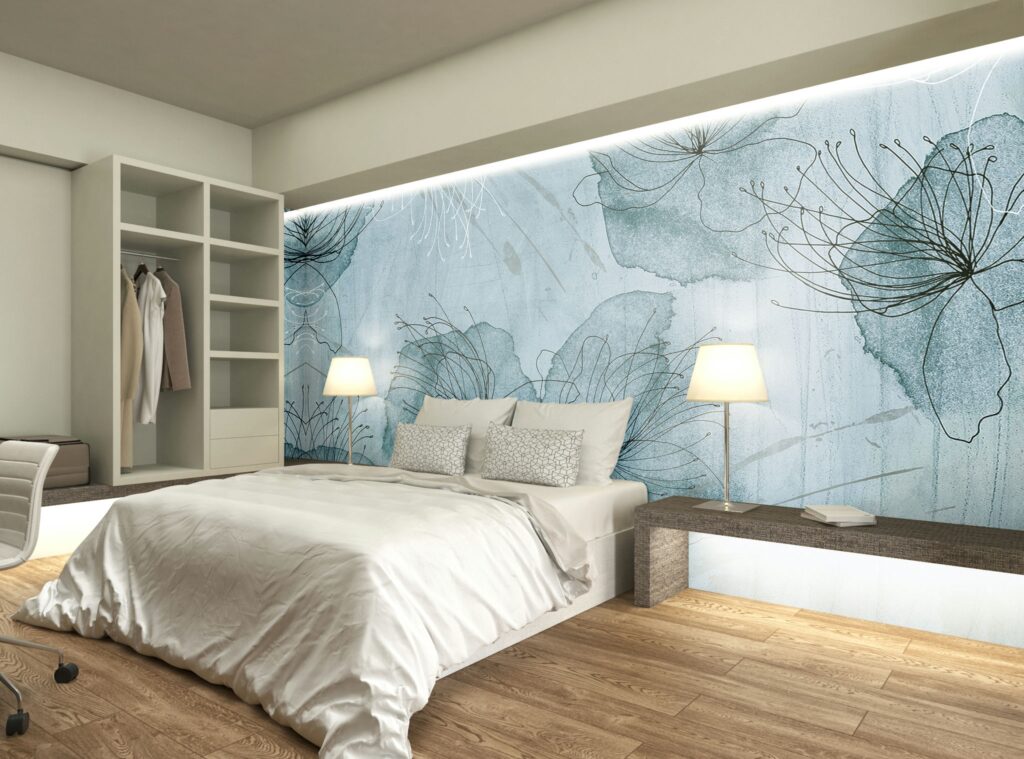 Diseño de interiores moderno en una habitación de alta gama en Barcelona Interior de un dormitorio moderno en Barcelona con un diseño de alta gama. Presenta una cama twin con un suave edredón, almohadas elegantes y un banco de madera minimalista, iluminado por luz natural. Mural floral azul claro en la pared, armario abierto con ropa organizada y suelo de madera cálido.