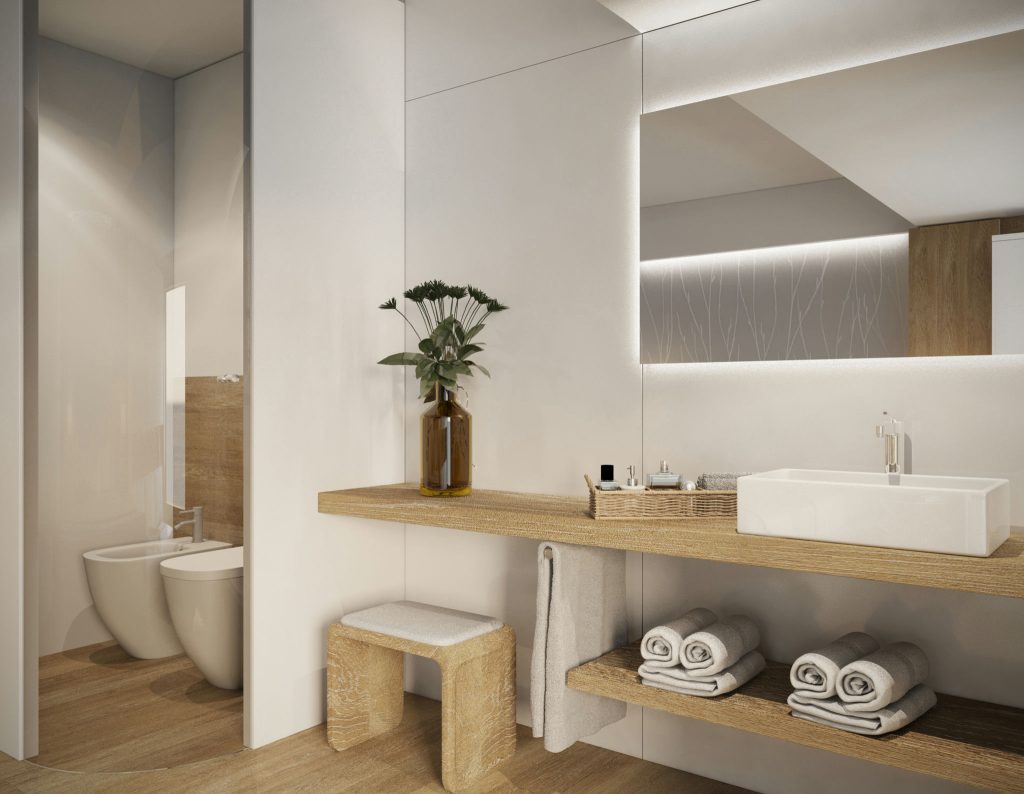Baño Moderno de Lujo en Barcelona: Diseño de Interiores Contemporáneo Vista interior de un baño moderno y de alta gama en Barcelona, con estantería de madera, lavabo blanco contemporáneo y decoración minimalista, resaltando materiales de calidad y luz natural.