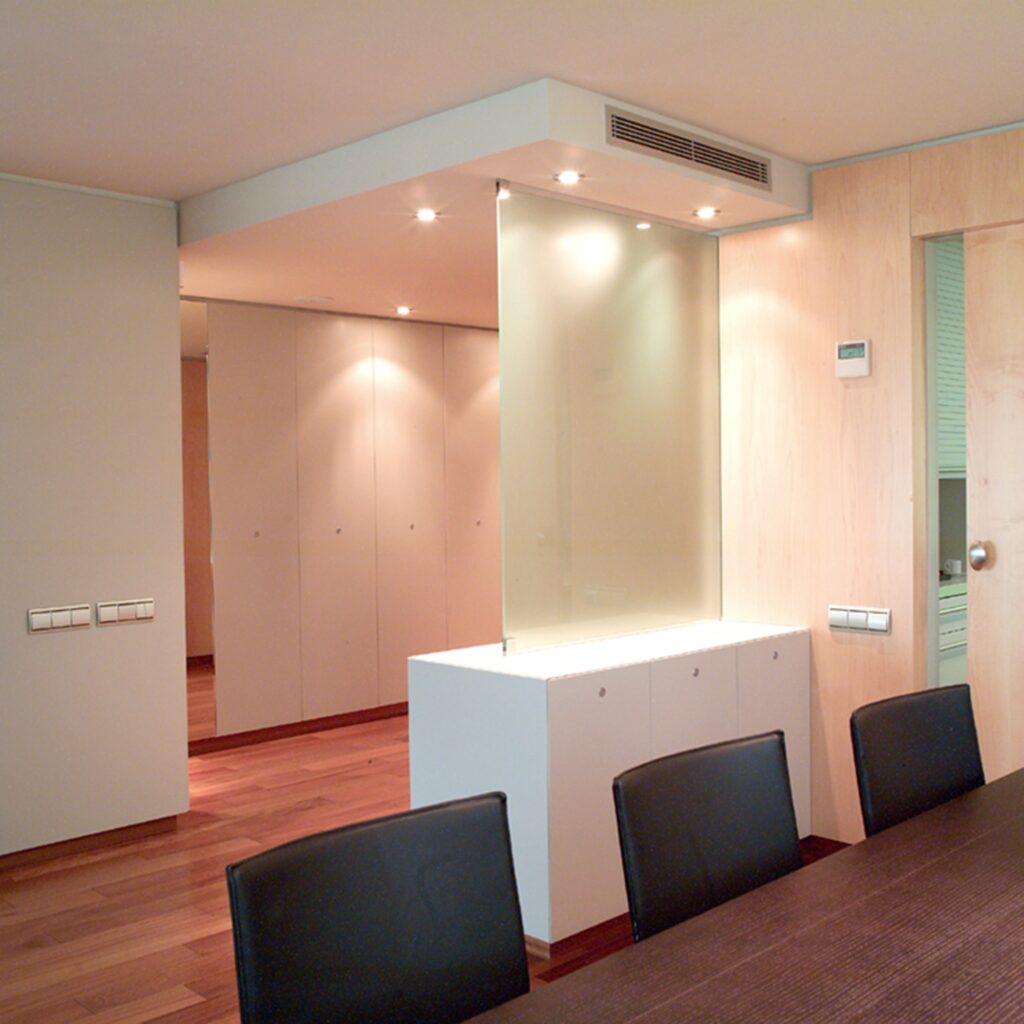 Interior de Oficina Moderna con Diseño Minimalista y Suelo de Madera Pulido Espacio de oficina contemporáneo que presenta una larga mesa de madera oscura con sillas negras, suelo de madera pulido y paredes de color claro. El interior incluye una partición de vidrio esmerilado y luces empotradas en el techo para crear una atmósfera cálida.