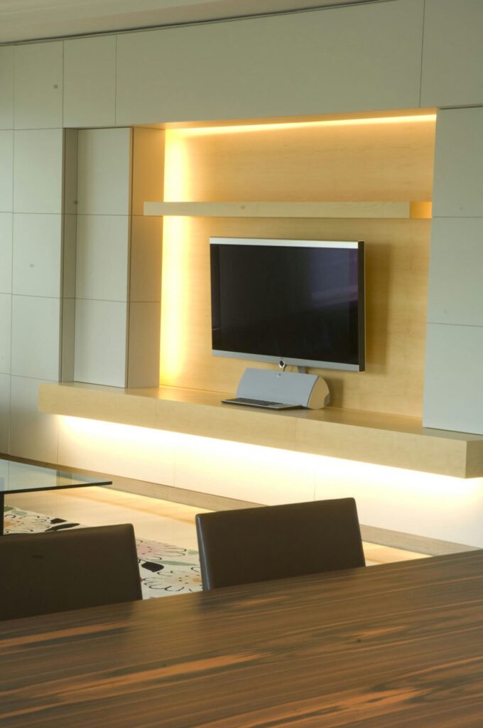 Diseño de interiores moderno en Barcelona: Proyecto de arquitectura de alta gama Espacio de vida contemporáneo en Barcelona que muestra un diseño de interiores minimalista, con una televisión montada en una pared de madera iluminada cálidamente, un elegante consola y una mesa de comedor moderna en primer plano.