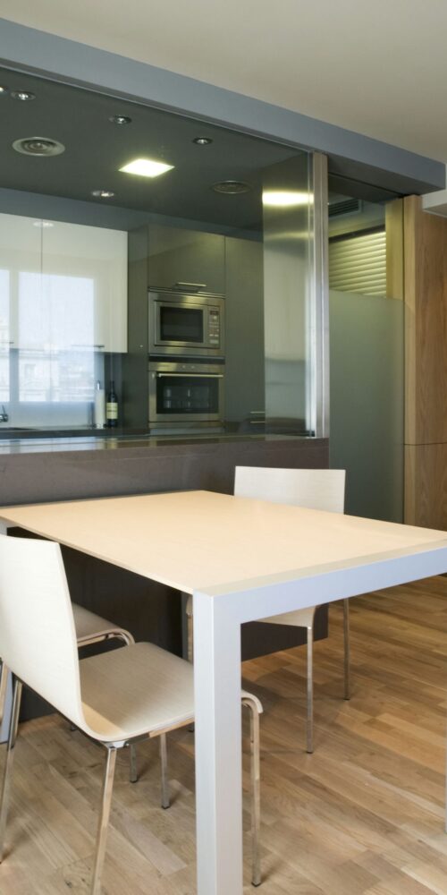 Piso en Av. Diagonal: Una cocina y comedor modernos y elegantes con un diseño minimalista, un suelo de madera clara, una mesa rectangular con cuatro sillas blancas y una cabinetry elegante.