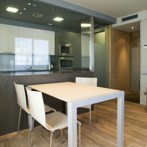 Piso en Av. Diagonal: Una cocina y comedor modernos y elegantes con un diseño minimalista, un suelo de madera clara, una mesa rectangular con cuatro sillas blancas y una cabinetry elegante.