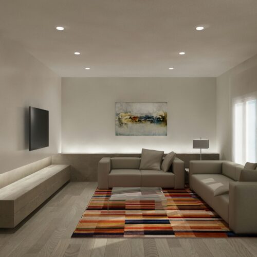 Interior de una moderna sala de estar en Barcelona, con un sofá seccional elegante y una alfombra geométrica colorida, resaltando la arquitectura contemporánea y la funcionalidad en el diseño.