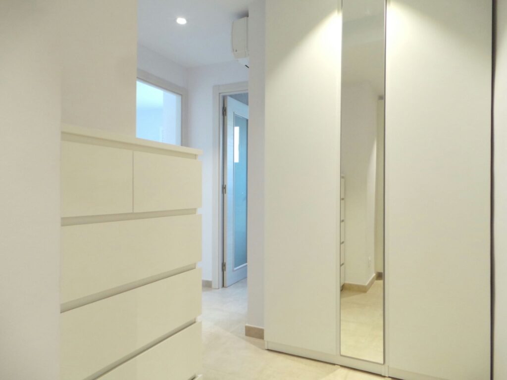 Diseño de interiores moderno en un espacio residencial de alta gama en Barcelona Interior elegante y minimalista de un hogar de alta gama en Barcelona, con paredes claras y piso de mármol, que destaca un mueble blanco y un armario espejado