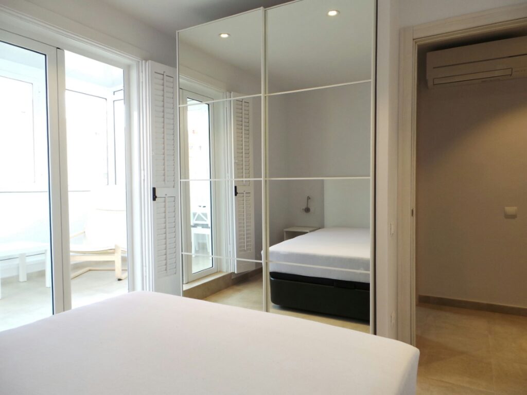 Dormitorio moderno de alta gama en Barcelona con diseño minimalista Interior de un dormitorio moderno en Barcelona, destacado por un armario grande con espejos, colores neutros y luz natural abundante.