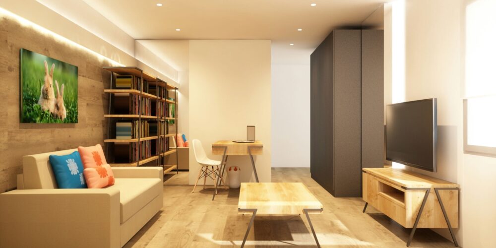 Proyecto de diseño de interiores en Barcelona con una sala de estar moderna y acogedora, que presenta un sofá claro con cojines coloridos, una mesa de café de madera y una estantería elegante, iluminada por luz natural.